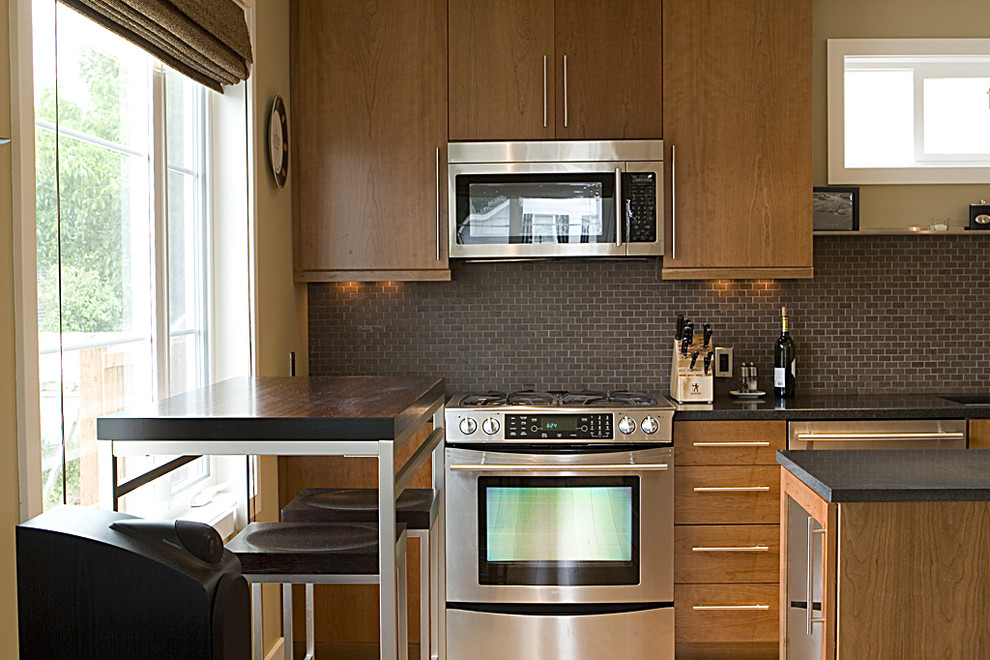 Modelo de cocina minimalista con electrodomésticos de acero inoxidable, armarios con paneles lisos, puertas de armario de madera oscura, salpicadero marrón, salpicadero de pizarra y cortinas