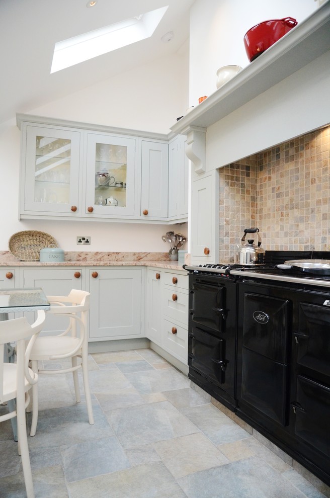 Klassische Küche mit Schrankfronten im Shaker-Stil, weißen Schränken, Küchenrückwand in Beige, Rückwand aus Mosaikfliesen und schwarzen Elektrogeräten in Cornwall