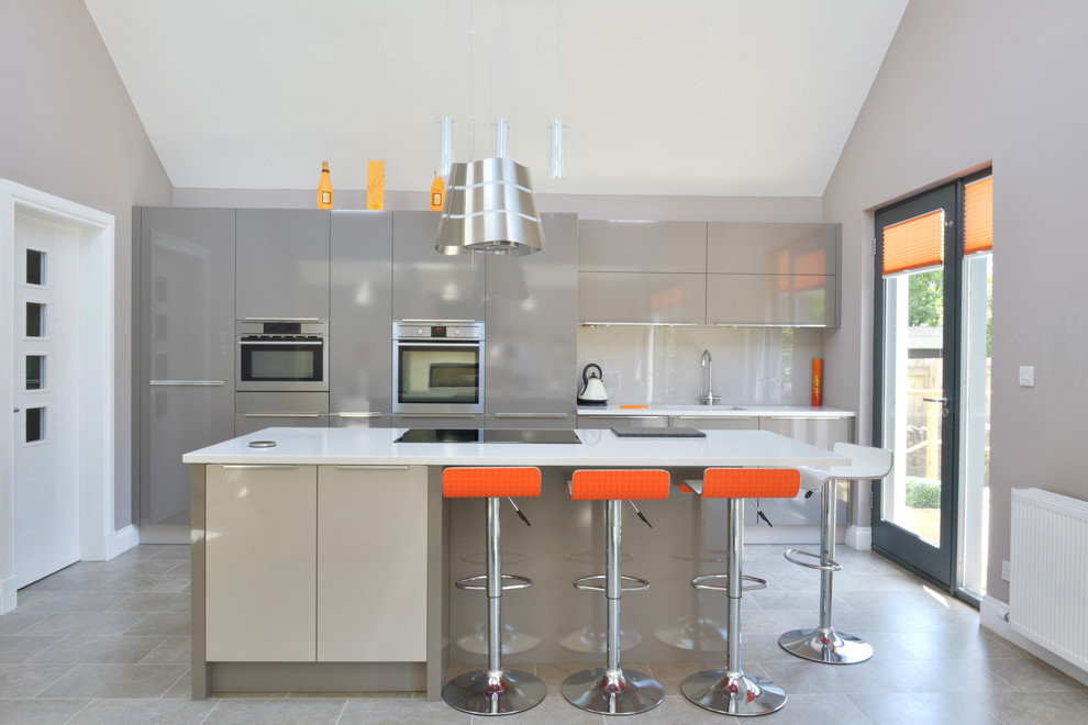 Medium sized contemporary single-wall open plan kitchen in Other with an integrated sink, flat-panel cabinets, beige cabinets, composite countertops, beige splashback, glass sheet splashback, integrated appliances, ceramic flooring, a breakfast bar and beige floors.