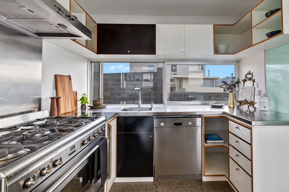 Esempio di una cucina moderna di medie dimensioni con lavello integrato, ante lisce, ante grigie, top in acciaio inossidabile, pavimento in cemento, nessuna isola e top bianco