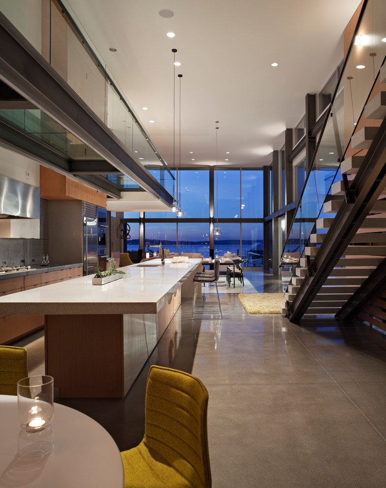 Cette image montre une cuisine ouverte parallèle minimaliste en bois brun avec un placard à porte plane, une crédence grise et un électroménager en acier inoxydable.