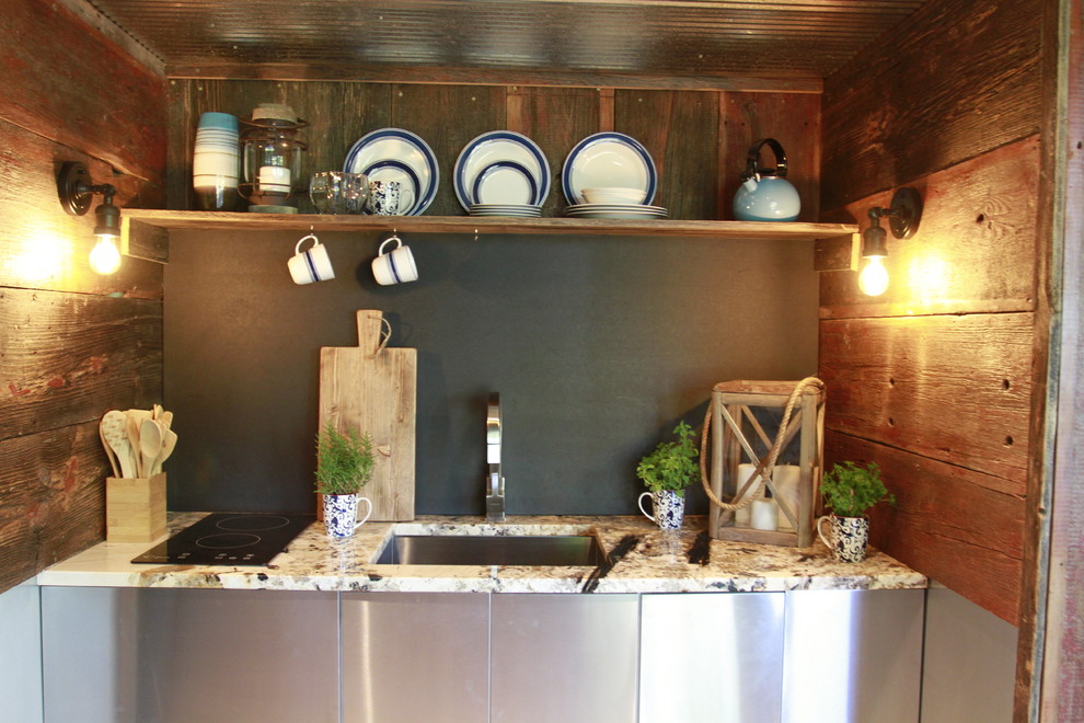 Foto di una piccola cucina rustica con lavello sottopiano, ante lisce, ante in acciaio inossidabile, top in granito, paraspruzzi nero, nessuna isola e parquet chiaro