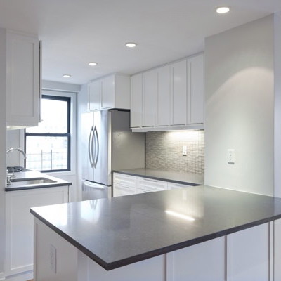Contemporary u-shaped kitchen/diner in New York with a submerged sink, recessed-panel cabinets, white cabinets, granite worktops, grey splashback, mosaic tiled splashback and stainless steel appliances.