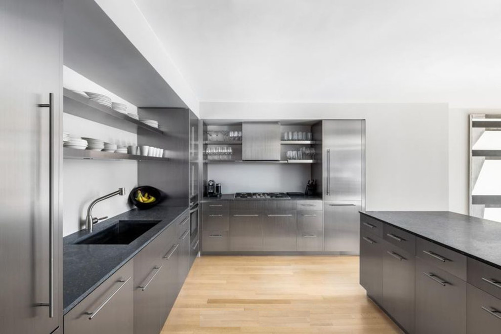 Inspiration for a large modern l-shaped kitchen/diner in New York with a submerged sink, flat-panel cabinets, stainless steel cabinets, onyx worktops, grey splashback, stainless steel appliances, medium hardwood flooring and an island.