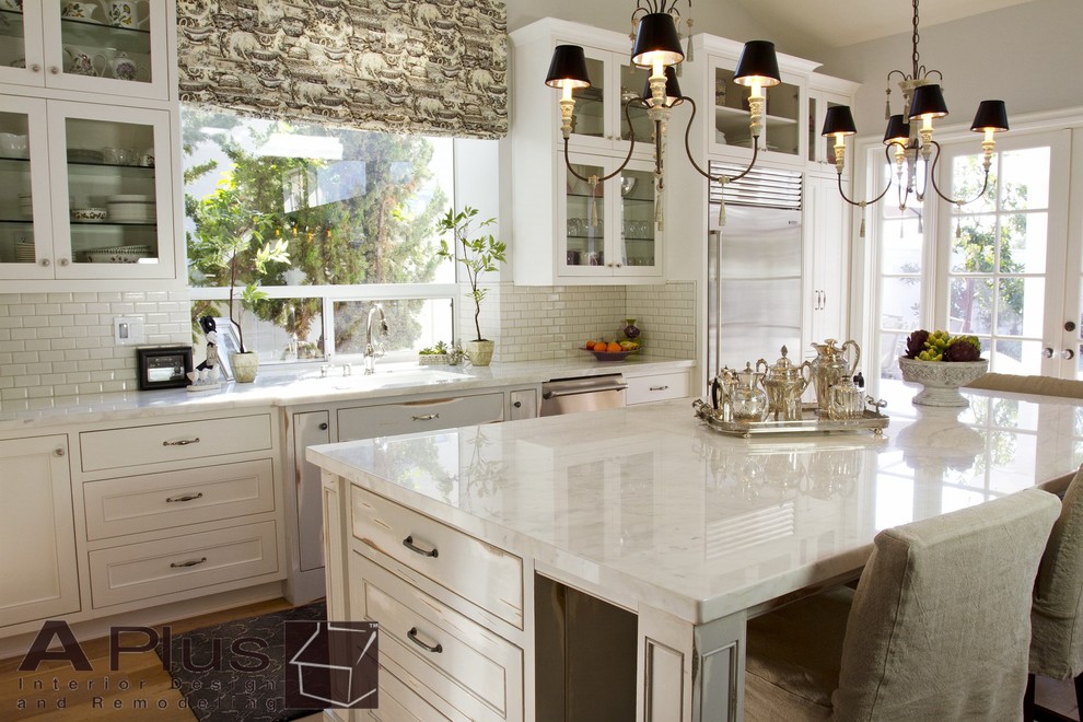 Large trendy single-wall medium tone wood floor eat-in kitchen photo in Orange County with a double-bowl sink, recessed-panel cabinets, white cabinets, quartz countertops, white backsplash, subway tile backsplash, white appliances and an island