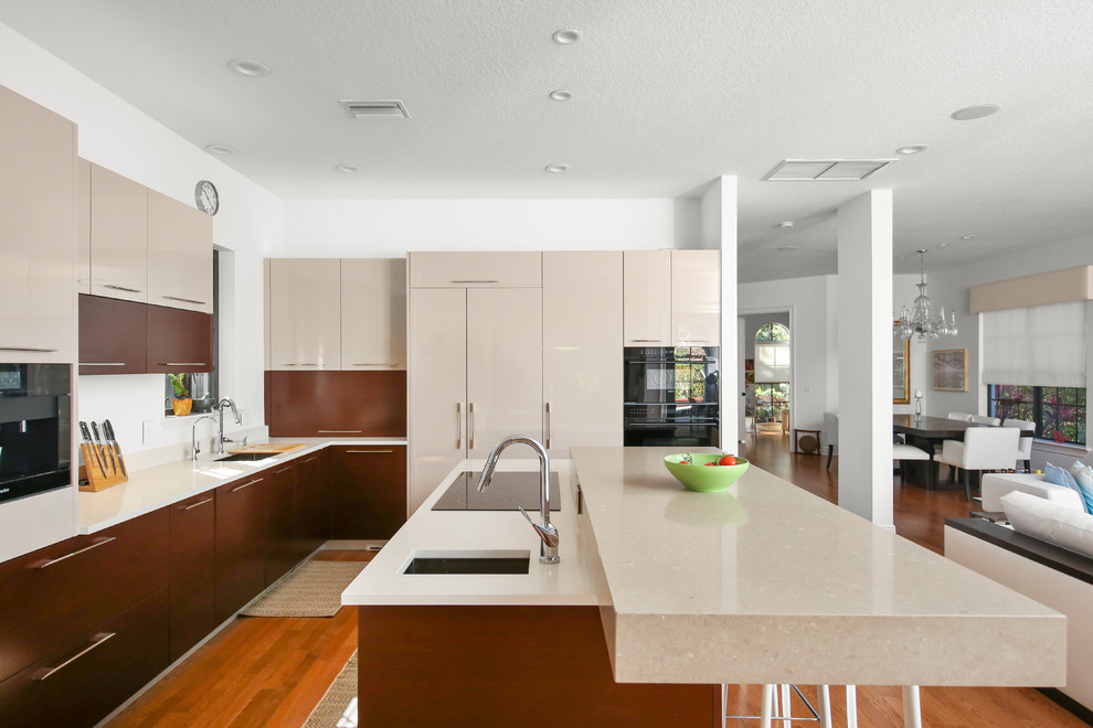 Immagine di una grande cucina minimal con ante lisce, ante beige, top in superficie solida, pavimento in legno massello medio, pavimento marrone, top bianco, lavello sottopiano e elettrodomestici da incasso