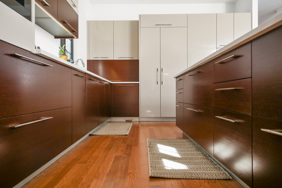 Immagine di una grande cucina design con ante lisce, ante beige, top in superficie solida, pavimento in legno massello medio, pavimento marrone, top bianco, lavello sottopiano e elettrodomestici da incasso