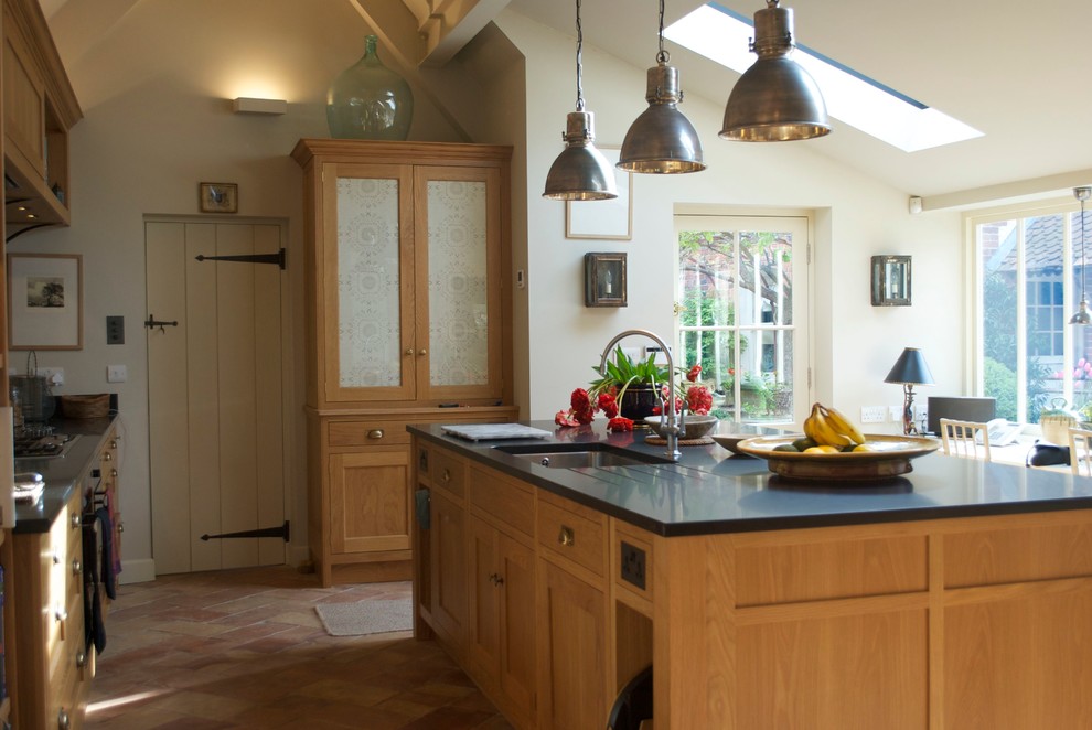 Einzeilige, Große Klassische Wohnküche mit Einbauwaschbecken, Glasfronten, hellbraunen Holzschränken, Granit-Arbeitsplatte, Rückwand aus Spiegelfliesen, Terrakottaboden und Kücheninsel in Wiltshire