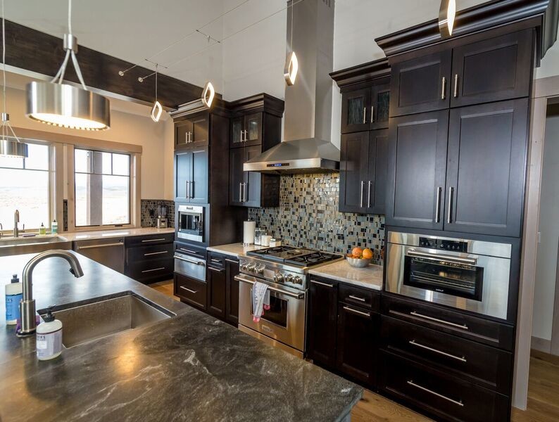 Large contemporary l-shaped kitchen in Denver with a submerged sink, shaker cabinets, dark wood cabinets, granite worktops, multi-coloured splashback, stainless steel appliances, medium hardwood flooring, an island and brown floors.