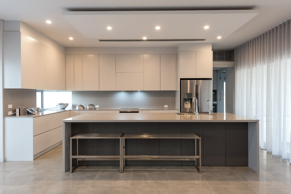 Contemporary l-shaped kitchen in Sydney with a submerged sink, flat-panel cabinets, grey cabinets, grey splashback, stainless steel appliances, concrete flooring, an island, grey floors and grey worktops.