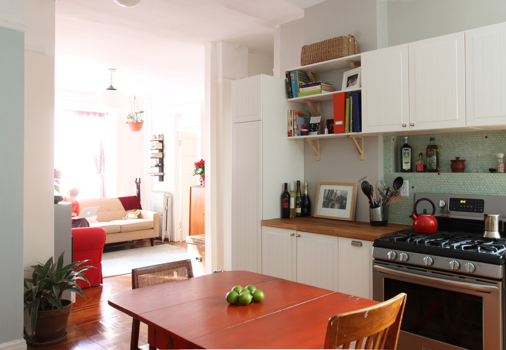 Foto på ett eklektiskt kök och matrum, med träbänkskiva, vita skåp, grönt stänkskydd, stänkskydd i mosaik och rostfria vitvaror