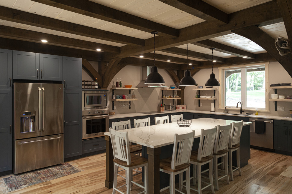 Inspiration for a large rustic l-shaped open plan kitchen in Toronto with shaker cabinets, engineered stone countertops, stainless steel appliances, light hardwood flooring, an island, beige floors, white worktops, a submerged sink and grey cabinets.