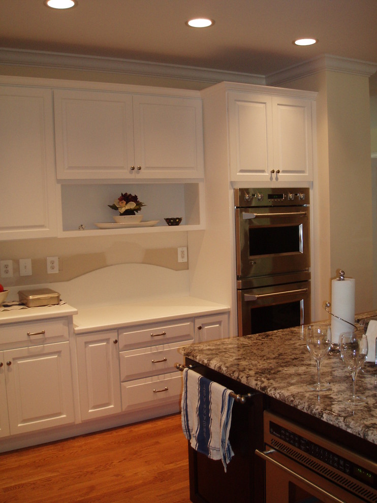 Klassisk inredning av ett mellanstort kök, med en undermonterad diskho, luckor med upphöjd panel, skåp i mörkt trä, bänkskiva i koppar, integrerade vitvaror, ljust trägolv och en köksö