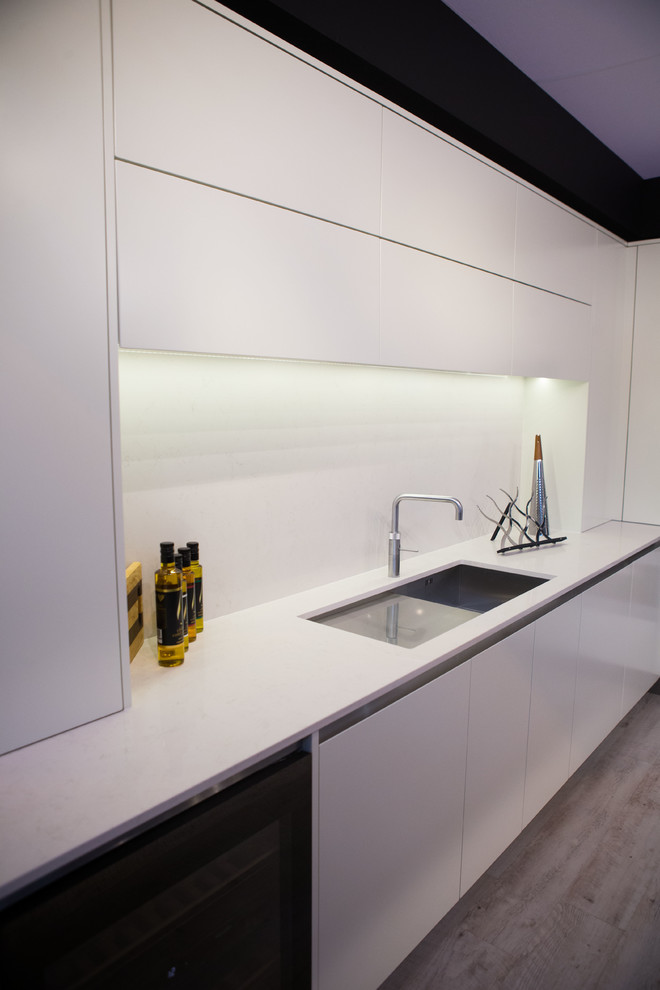 Immagine di una grande cucina contemporanea con lavello sottopiano, ante lisce, ante bianche, top in quarzite, paraspruzzi bianco, paraspruzzi con lastra di vetro, pavimento in compensato e elettrodomestici neri