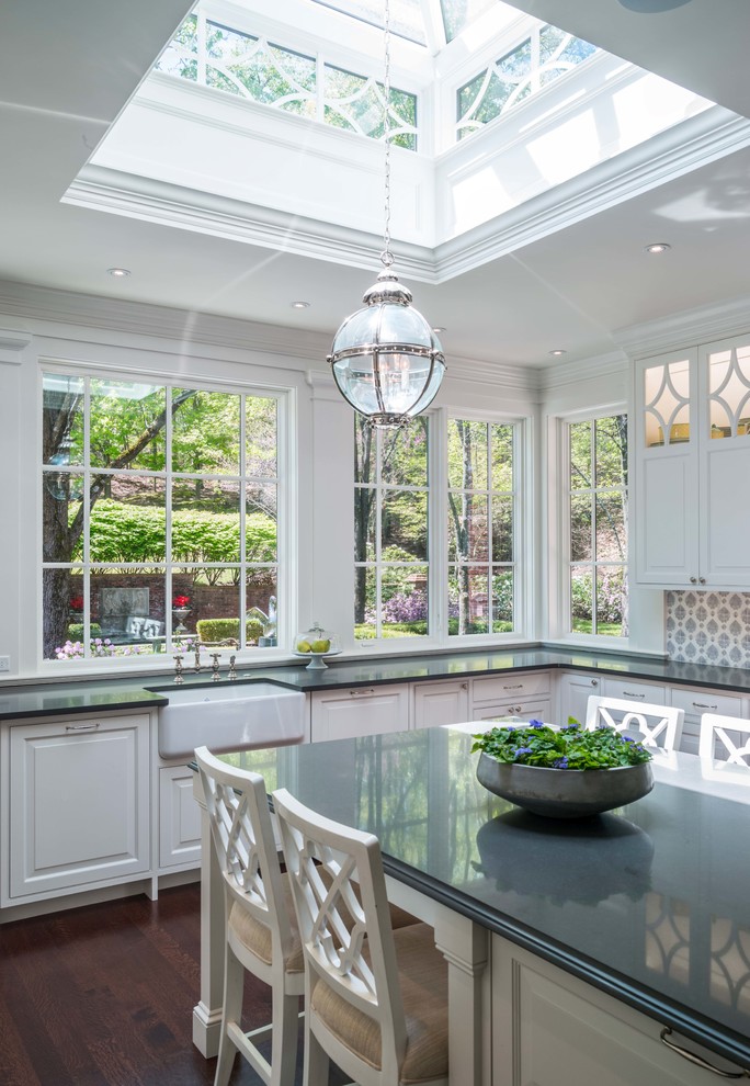 Enclosed kitchen - large traditional u-shaped medium tone wood floor and brown floor enclosed kitchen idea in Boston with a farmhouse sink, raised-panel cabinets, white cabinets, quartz countertops, blue backsplash, stone tile backsplash, stainless steel appliances and an island