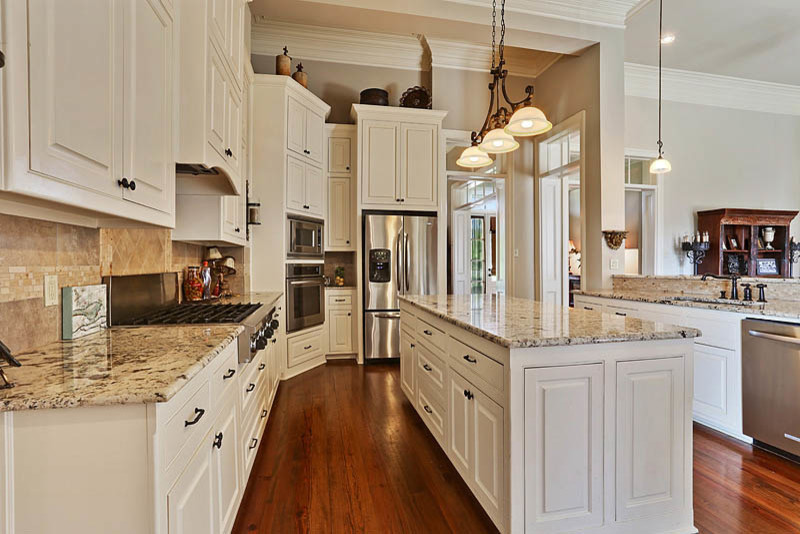 Exempel på ett mellanstort klassiskt kök, med luckor med upphöjd panel, vita skåp, granitbänkskiva, beige stänkskydd, stänkskydd i stenkakel, rostfria vitvaror, mellanmörkt trägolv och en köksö