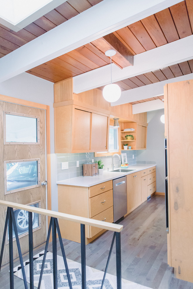 This is an example of a small midcentury galley enclosed kitchen in Grand Rapids with a built-in sink, flat-panel cabinets, light wood cabinets, laminate countertops, grey splashback, glass tiled splashback, stainless steel appliances, medium hardwood flooring, no island, grey floors and beige worktops.