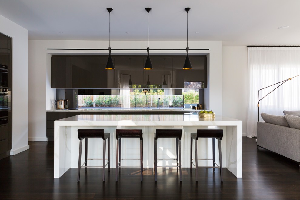 Diseño de cocina minimalista grande abierta con salpicadero de vidrio, suelo de madera oscura, una isla, suelo marrón, fregadero de doble seno y puertas de armario negras