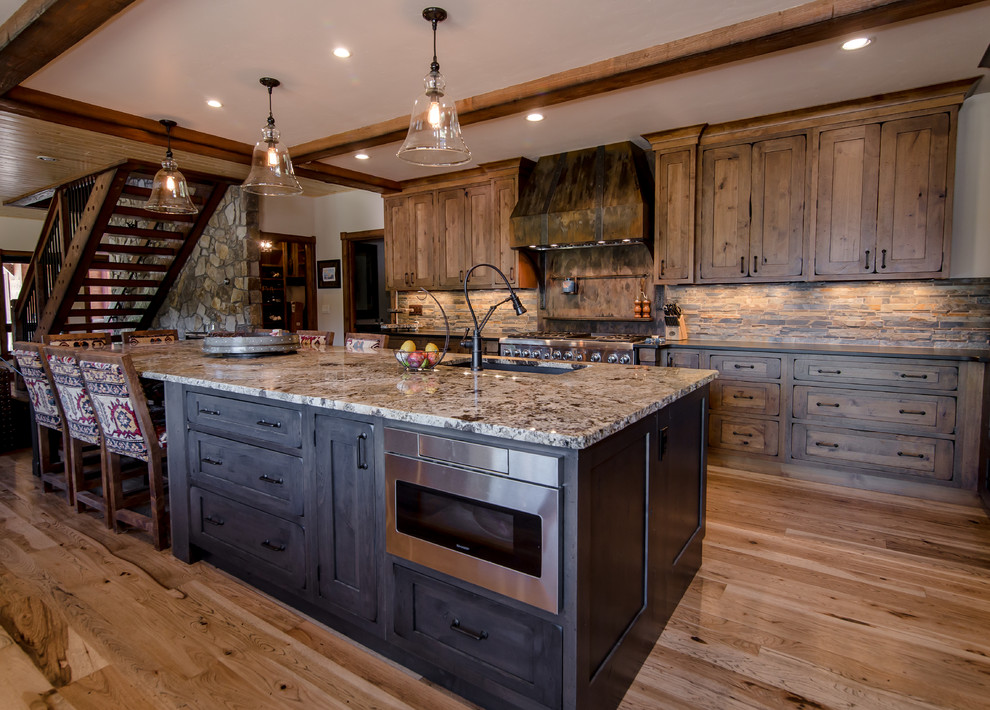 Rustik inredning av ett stort kök, med en nedsänkt diskho, skåp i shakerstil, bruna skåp, granitbänkskiva, rostfria vitvaror, mellanmörkt trägolv, en köksö och brunt golv