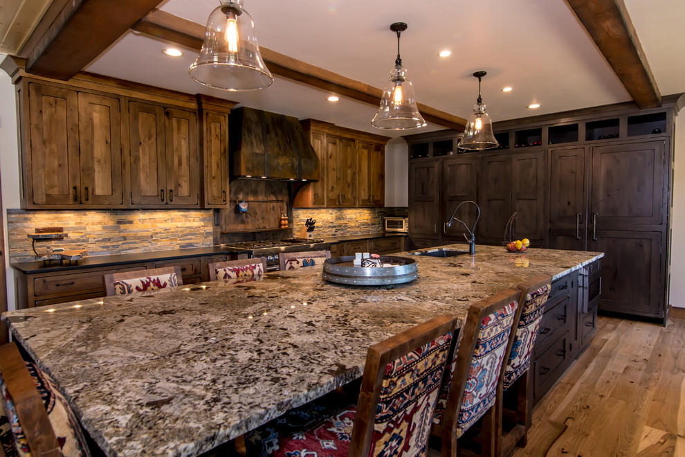 Example of a large mountain style u-shaped medium tone wood floor and brown floor open concept kitchen design in Denver with a drop-in sink, shaker cabinets, brown cabinets, granite countertops, stainless steel appliances and an island