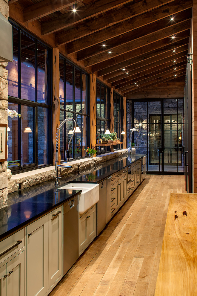 Foto di una cucina stile rurale con lavello stile country, ante grigie, elettrodomestici in acciaio inossidabile e pavimento in legno massello medio