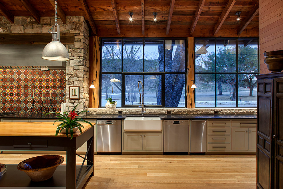 Diseño de cocina rural abierta con fregadero sobremueble, puertas de armario grises, electrodomésticos de acero inoxidable, suelo de madera en tonos medios y una isla