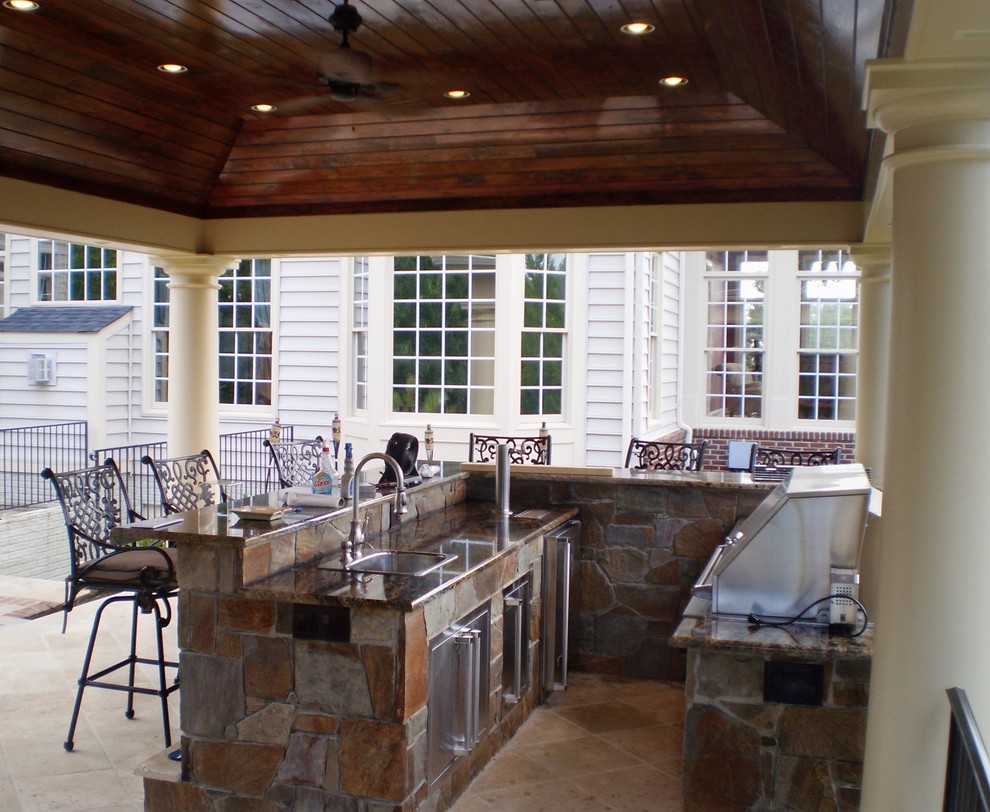 Klassisk inredning av ett stort kök, med skåp i rostfritt stål, granitbänkskiva, stänkskydd i stenkakel, rostfria vitvaror, marmorgolv och en halv köksö
