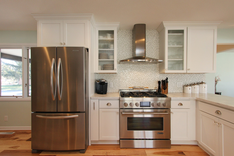 Imagen de cocina tradicional renovada con armarios estilo shaker, puertas de armario blancas, encimera de acrílico, salpicadero gris y electrodomésticos de acero inoxidable