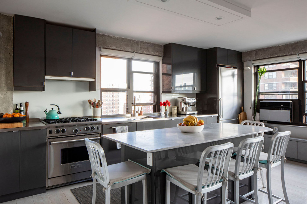 Industrial single-wall kitchen in New York with an integrated sink, flat-panel cabinets, grey cabinets, stainless steel appliances, light hardwood flooring, an island, grey floors and grey worktops.