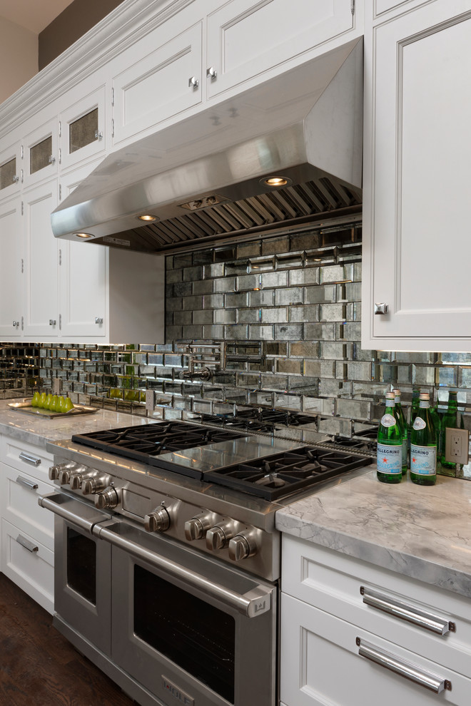 Foto på ett mellanstort eklektiskt kök, med en rustik diskho, luckor med infälld panel, vita skåp, bänkskiva i kvartsit, stänkskydd med metallisk yta, spegel som stänkskydd, integrerade vitvaror, mörkt trägolv och en köksö