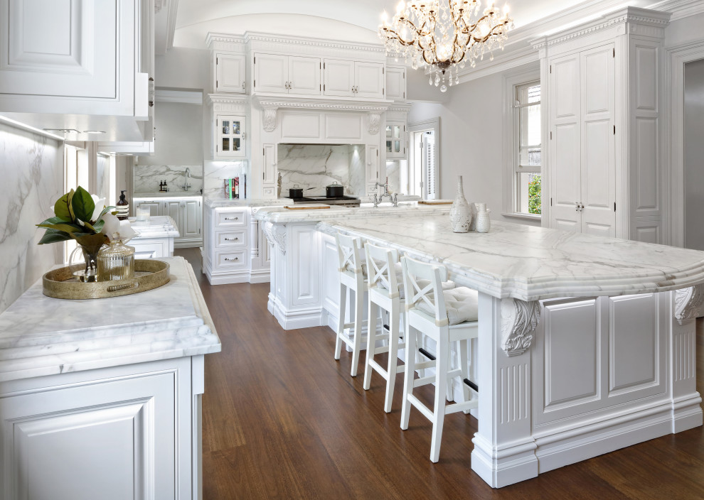 Exempel på ett mycket stort klassiskt vit vitt skafferi, med en rustik diskho, luckor med upphöjd panel, vita skåp, marmorbänkskiva, vitt stänkskydd, stänkskydd i marmor, rostfria vitvaror, mörkt trägolv, en köksö och brunt golv