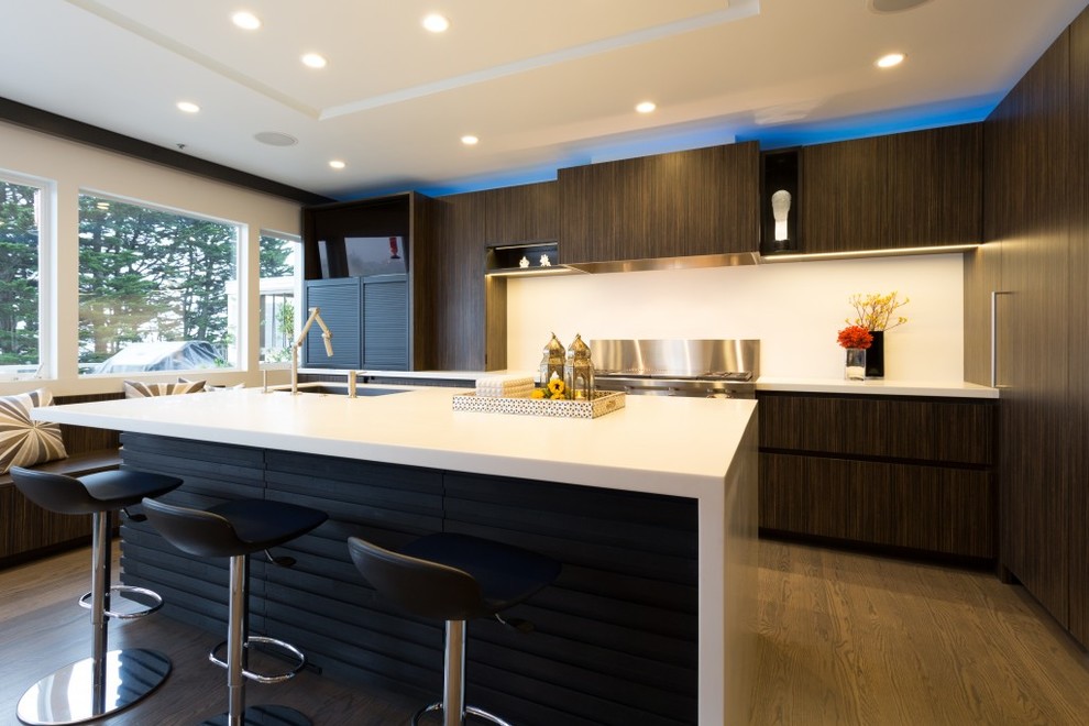 Design ideas for a large contemporary l-shaped open plan kitchen in San Francisco with a submerged sink, flat-panel cabinets, dark wood cabinets, engineered stone countertops, white splashback, stone slab splashback, integrated appliances, medium hardwood flooring and an island.