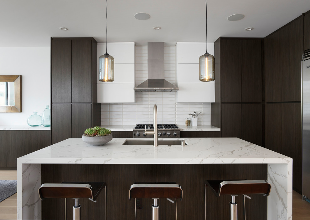 Moderne Küche mit Unterbauwaschbecken, flächenbündigen Schrankfronten, dunklen Holzschränken, Küchenrückwand in Weiß, Küchengeräten aus Edelstahl, Kücheninsel und weißer Arbeitsplatte in San Francisco