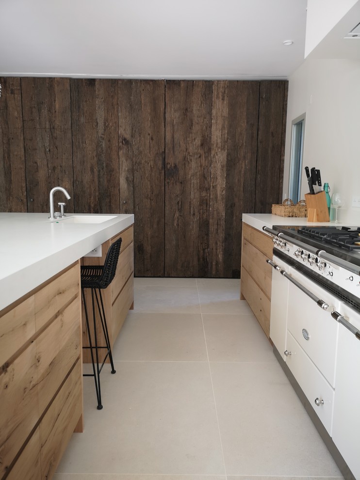 Modern inredning av ett stort beige beige kök, med en undermonterad diskho, släta luckor, skåp i ljust trä, kaklad bänkskiva, vitt stänkskydd, vita vitvaror, travertin golv, en köksö och beiget golv