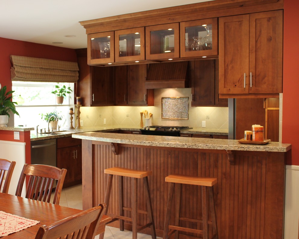 Bild på ett avskilt, litet amerikanskt u-kök, med en undermonterad diskho, skåp i mellenmörkt trä, granitbänkskiva, beige stänkskydd, rostfria vitvaror, skåp i shakerstil, stänkskydd i keramik, klinkergolv i keramik och en halv köksö