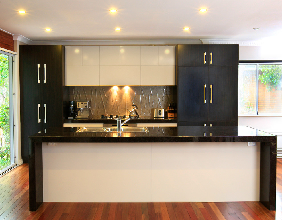 Modern inredning av ett mellanstort kök, med en dubbel diskho, släta luckor, skåp i mörkt trä, granitbänkskiva, beige stänkskydd, glaspanel som stänkskydd, rostfria vitvaror, ljust trägolv och en köksö