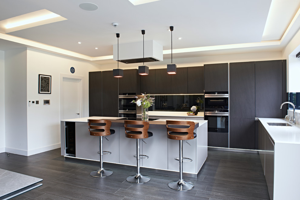 Moderne Küche in L-Form mit Unterbauwaschbecken, flächenbündigen Schrankfronten, schwarzen Schränken, Kücheninsel und grauem Boden in London