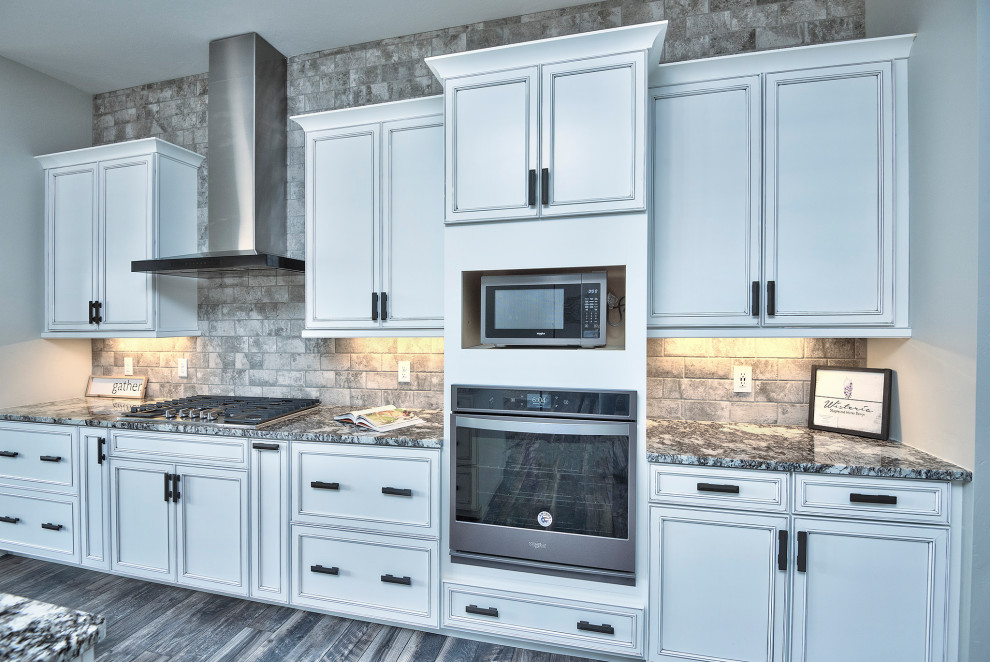 Idéer för ett stort amerikanskt flerfärgad kök, med en undermonterad diskho, luckor med infälld panel, vita skåp, laminatbänkskiva, grått stänkskydd, stänkskydd i stenkakel, rostfria vitvaror, mellanmörkt trägolv, en köksö och flerfärgat golv