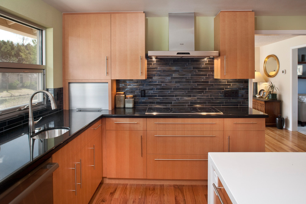 Foto på ett mellanstort funkis kök, med en undermonterad diskho, släta luckor, skåp i ljust trä, bänkskiva i kvarts, svart stänkskydd, stänkskydd i stenkakel, rostfria vitvaror, ljust trägolv och en köksö