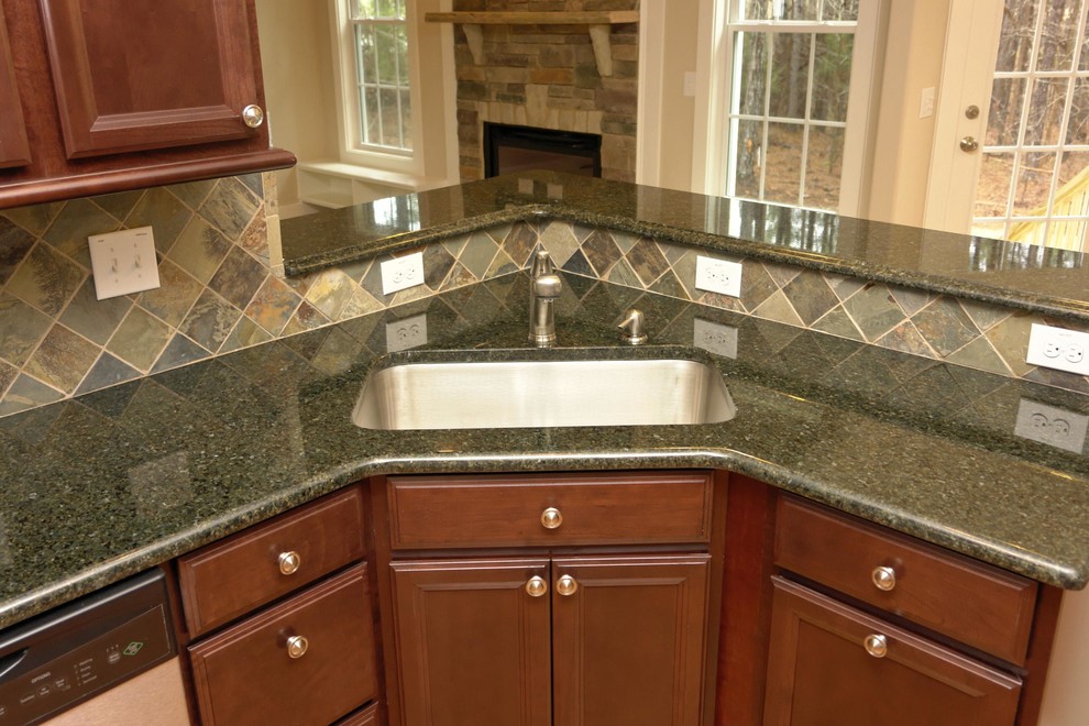 Inspiration for a mid-sized timeless u-shaped medium tone wood floor enclosed kitchen remodel in Raleigh with a single-bowl sink, recessed-panel cabinets, dark wood cabinets, granite countertops, blue backsplash, stainless steel appliances and an island