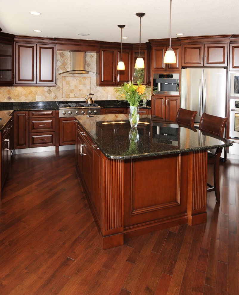 Inspiration for a large timeless u-shaped dark wood floor enclosed kitchen remodel in Toronto with raised-panel cabinets, dark wood cabinets, granite countertops, beige backsplash, stone tile backsplash, stainless steel appliances and an island