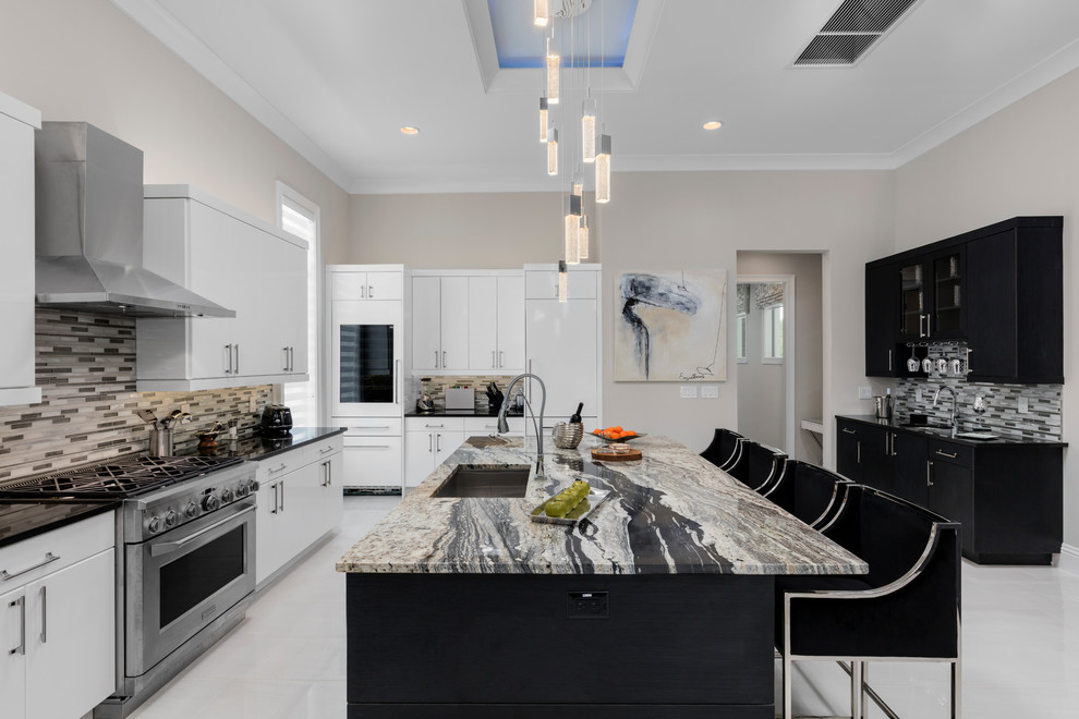 Exempel på ett modernt kök, med en undermonterad diskho, släta luckor, vita skåp, flerfärgad stänkskydd, stänkskydd i stickkakel, rostfria vitvaror, en köksö och vitt golv