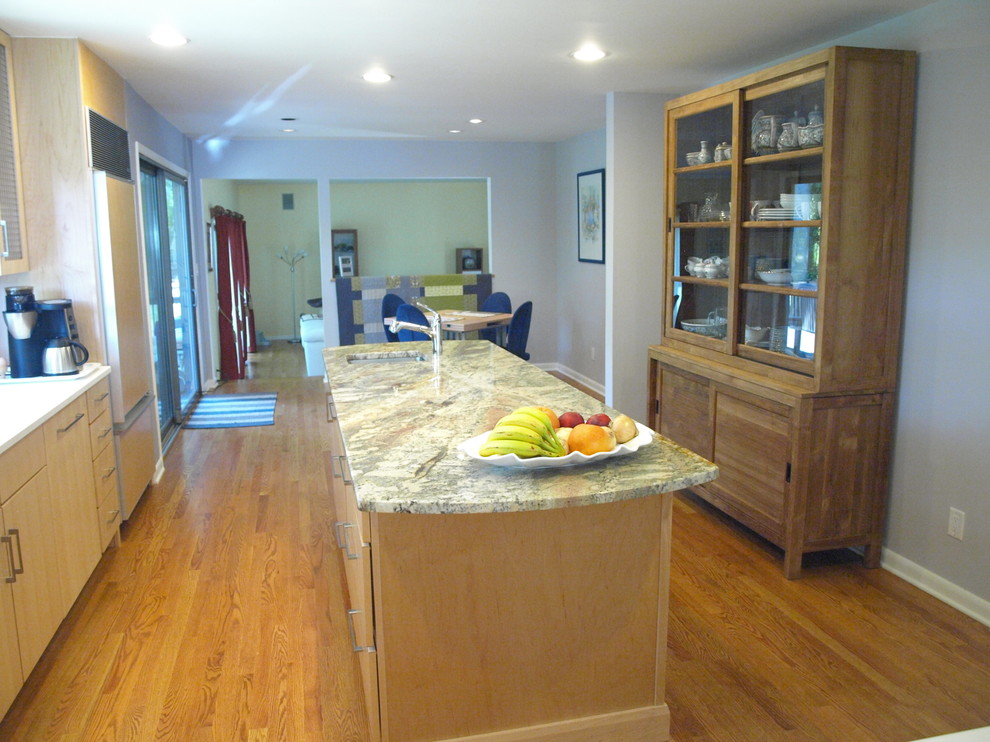 Immagine di una cucina minimalista di medie dimensioni con lavello da incasso, ante lisce, ante in legno chiaro, top in granito, elettrodomestici in acciaio inossidabile e parquet chiaro