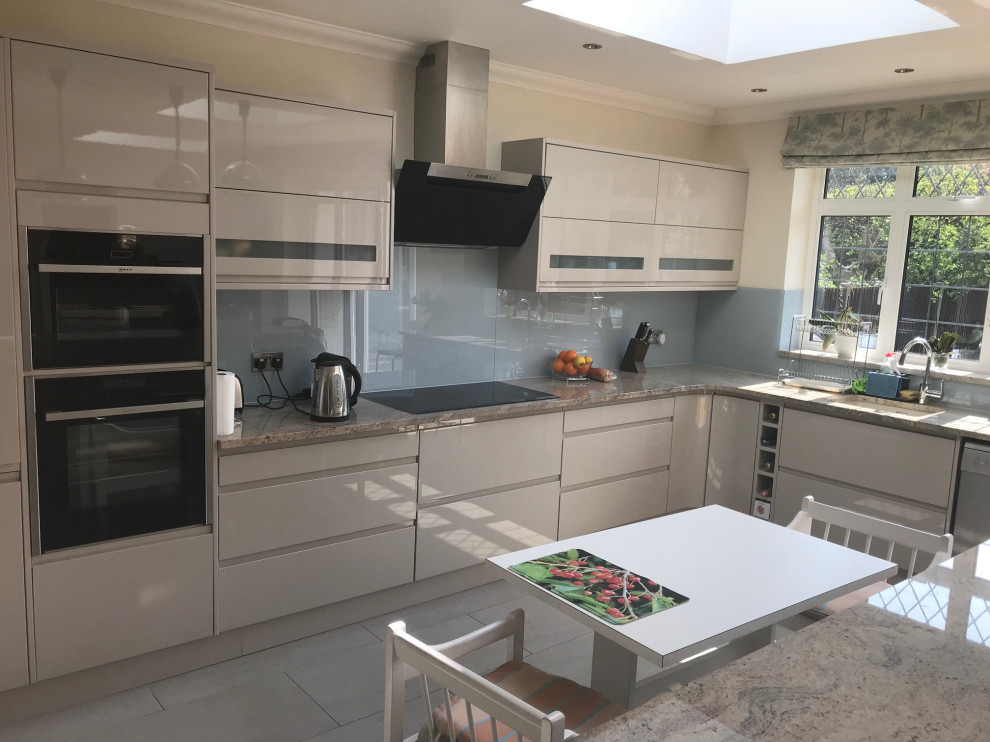 Große Moderne Küche mit Granit-Arbeitsplatte, Küchenrückwand in Grün, Glasrückwand, Kücheninsel und beiger Arbeitsplatte in London