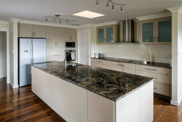Imagen de cocina actual con encimera de granito, fregadero bajoencimera, suelo de bambú y electrodomésticos de acero inoxidable