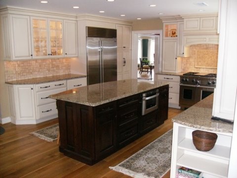 This is an example of a traditional kitchen in Philadelphia with a submerged sink, raised-panel cabinets, white cabinets, beige splashback, ceramic splashback, stainless steel appliances, light hardwood flooring, an island and beige floors.