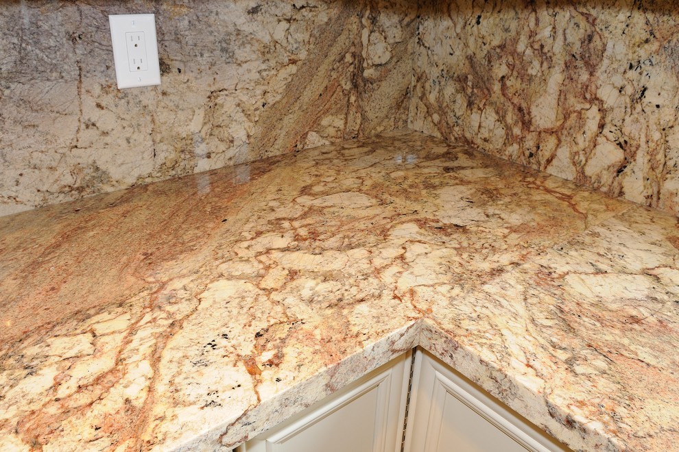 Inredning av ett modernt mellanstort kök, med en dubbel diskho, luckor med profilerade fronter, vita skåp, granitbänkskiva, flerfärgad stänkskydd, stänkskydd i sten, rostfria vitvaror, marmorgolv och brunt golv