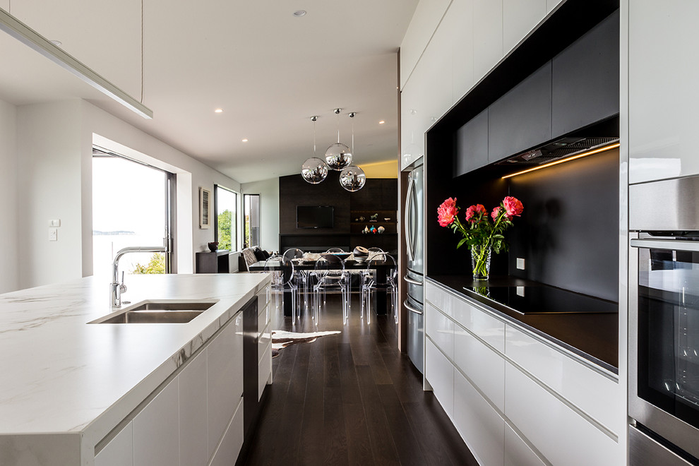 Immagine di una cucina minimal di medie dimensioni con lavello sottopiano, ante lisce, ante bianche, paraspruzzi nero, elettrodomestici in acciaio inossidabile e parquet scuro
