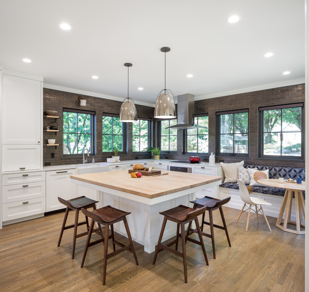 Klassische Küche in L-Form mit Landhausspüle, Schrankfronten im Shaker-Stil, weißen Schränken, hellem Holzboden und Kücheninsel in Portland
