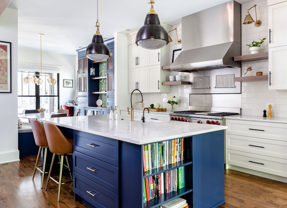 Example of a transitional brown floor, medium tone wood floor and exposed beam eat-in kitchen design in Atlanta with a farmhouse sink, shaker cabinets, white cabinets, white backsplash, subway tile backsplash, stainless steel appliances, an island, white countertops and quartz countertops